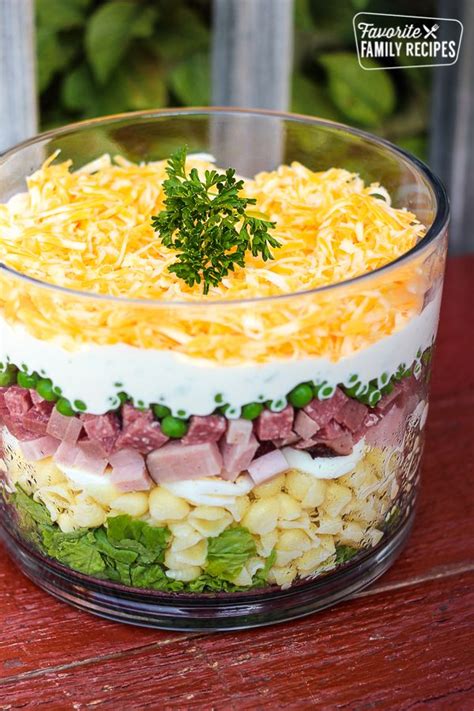 Healthy leftover creamy ham pasta with peas. Layered Pasta Salad with ham, peas, noodles in a glass dish topped with cheese and a garnsih ...