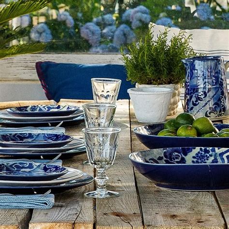 An Outdoor Table Set With Blue And White Dishes Glasses Limes And Cups
