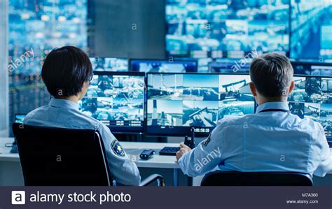 In The Security Control Room Two Officers Monitoring Multiple Screens
