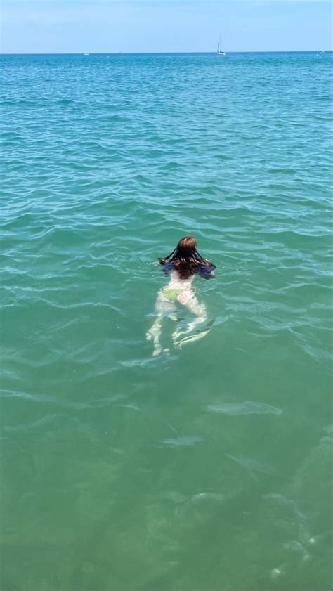 A Woman Swimming In The Ocean With Her Back To The Camera And Head