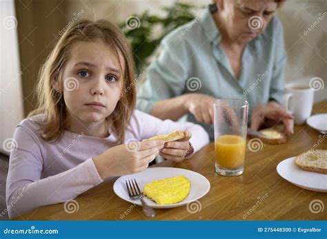 a little blonde girl is having breakfast in the kitchen with her beloved grandmother with an