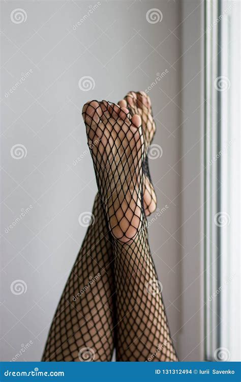 Female Feet And Soles In Black Fishnet On Window Background Royalty