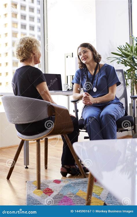 Senior Woman Having Consultation With Female Doctor Wearing Scrubs In