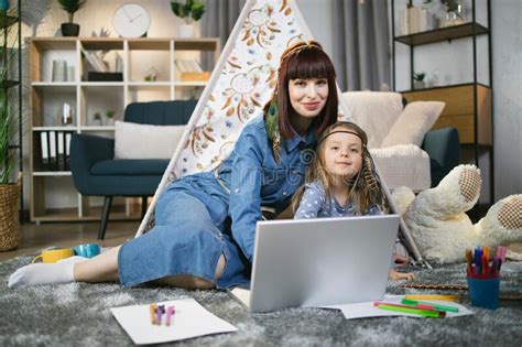 Woman And Child Sitting Near Teepee And Using Laptop Stock Photo