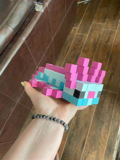 A Hand Holding A Small Pink And Blue Blocky Paper Toy In Its Palm