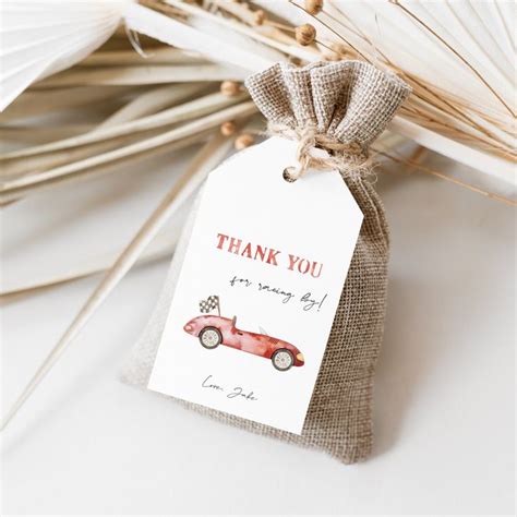 A Thank You Tag With A Red Car On It Next To Some Grass And Palm Leaves