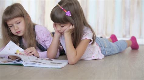 Two Little Girls Reading A Book Lying On The Floor Stock Video Footage