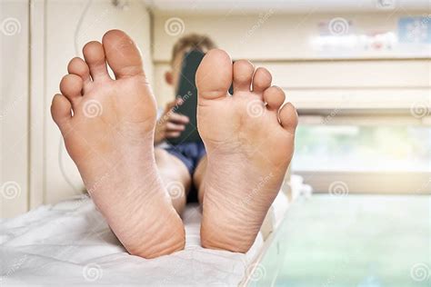 Bare Feet Of Boy Lying On Bed And Playing Games On Tablet Stock Image