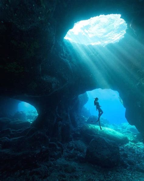 A Person Swimming In An Underwater Cave With Sunlight Streaming Through