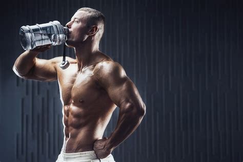 Premium Photo Fit Man At Workout In Gym With Shaker On Dark Background