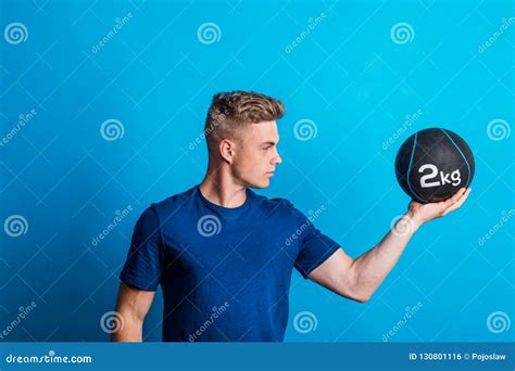 Portrait Of A Young Man Holding A Heavy Ball In One Hand In A Studio