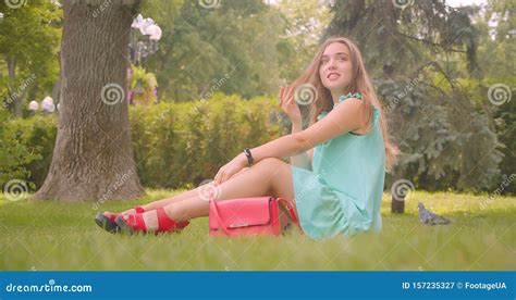 Closeup Portrait Of Young Long Haired Beautiful Female Sitting On Grass