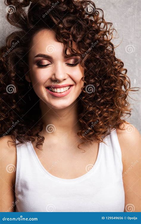 portrait of beautiful cheerful girl with flying curly hair smiling laughing looking at camera