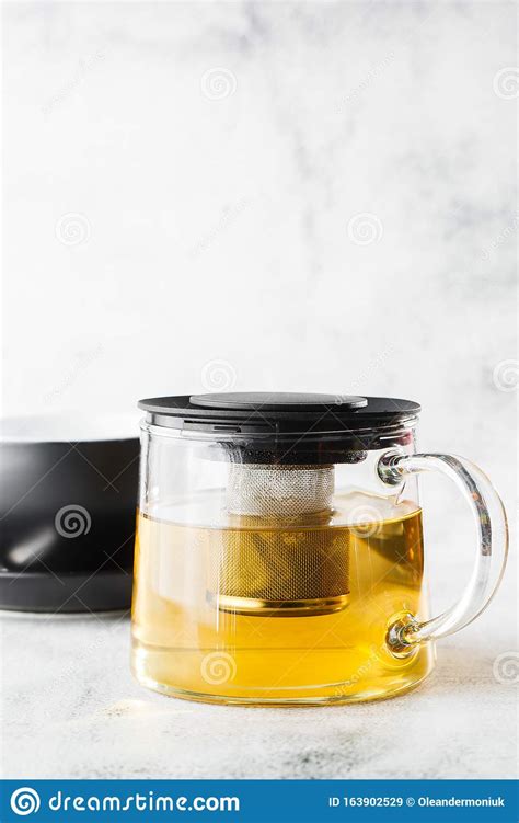 Glass Teapot With Dark Cup Of Green Camomile Chamomile Or Yellow Tea