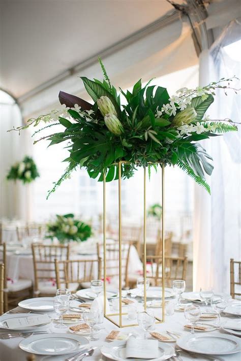 A Tall Centerpiece On A Gilded Stand With Lush Greenery White Blooms
