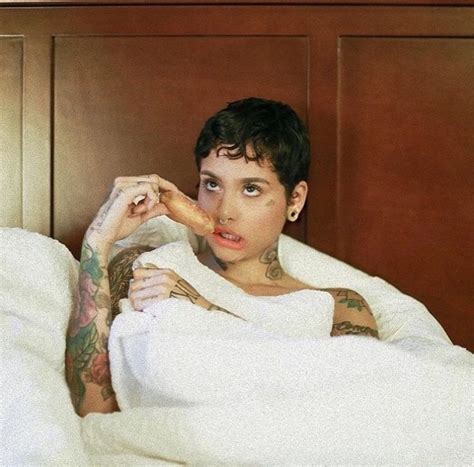 A Woman Laying In Bed Covered By A Blanket With Tattoos On Her Arms And