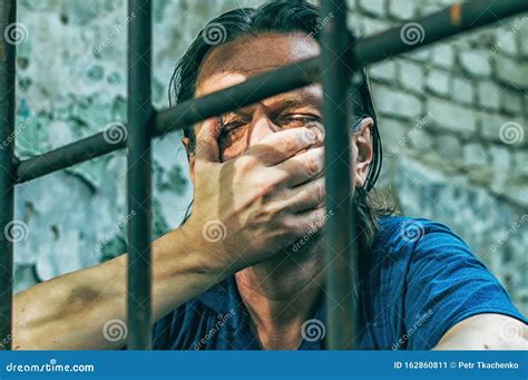 A Depressed Man Holds His Hands on the Prison Bars. Prisoner for the