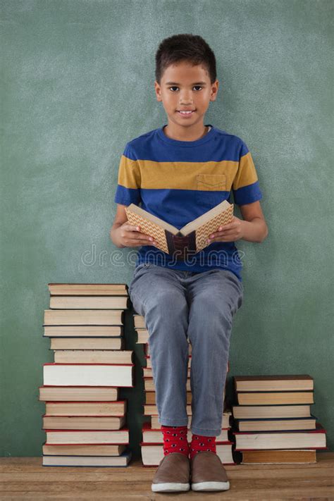 Schoolboy Sitting On Books Stack And Reading Book Stock Image Image