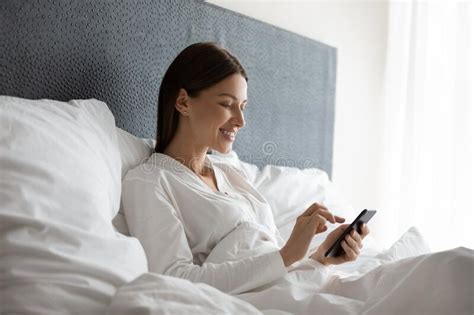 Happy Attractive Brunette Woman Using Mobile Phone After Wake Up Stock