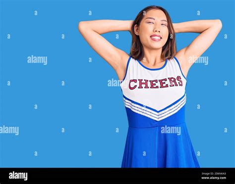 Young Beautiful Chinese Girl Wearing Cheerleader Uniform Relaxing And