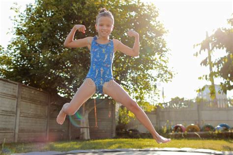 Little Sports Girl Jumps On A Trampoline Outdoor Shot Of Girl Jumping On Trampoline Enjoys