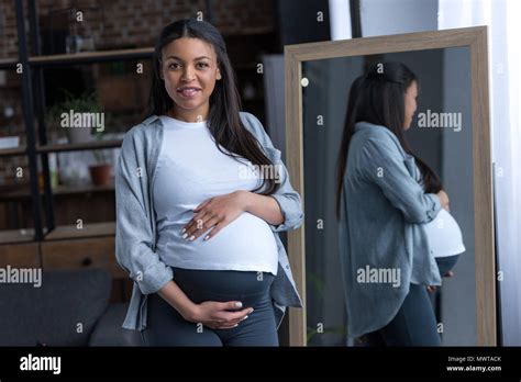 African American Pregnant Woman With Big Belly Standing At Mirror Stock