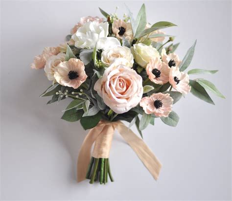 a bouquet of white and pink flowers with green leaves on a gray background for a wedding or bridal