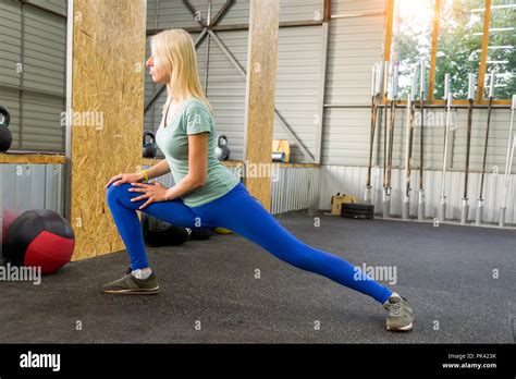 Blond Girl In Blue Leggins Is Doing Stretching By Lashes Raising Her