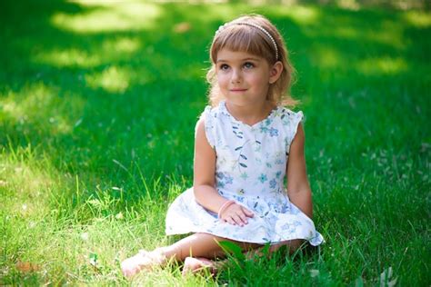 Retrato De Una Niña Sonriente Que Se Sienta En Hierba Verde Foto Premium