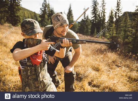 Father Teaching Son With Rifle Hunting In Sunny Field Stock Photo Alamy