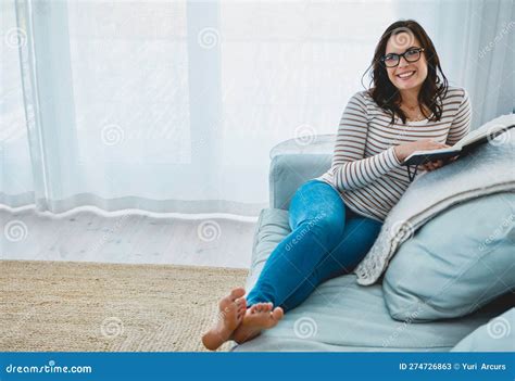 Unwinding With My Favorite Author A Young Woman Relaxing On The Sofa And Reading A Book At Home