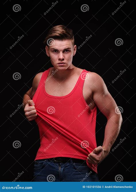 Healthy Beautiful Young Man Pulling His Red T Shirt On A Black