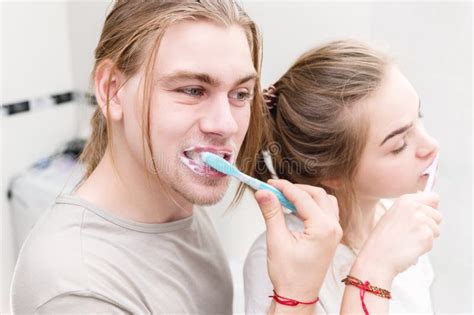 Young Attractive Couple Man And Woman Brush Their Teeth In The Bathroom Oral Care Concept In