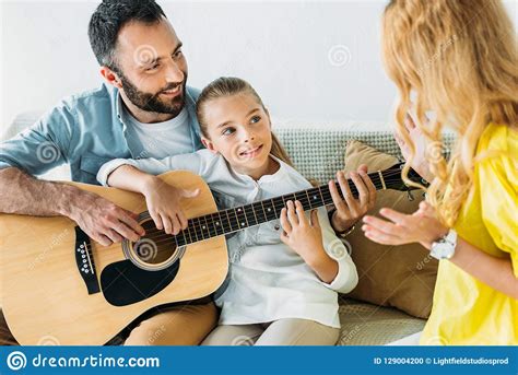 Padre E Hija Que Tocan La Guitarra Para La Madre Foto De Archivo