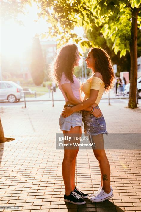 Lesbians Looking At Each Other While Standing On Footpath In City During Sunny Day High Res