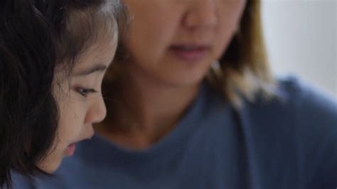 Close Up Of Little Asian Girl With Mother Doing Homework Stock Video