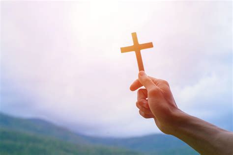 Man Praying With Cross While Holding A Crucifix Symbol With Bright