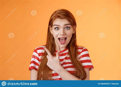 excited female redhead hear impressive sale offer pointing upper left corner drop jaw