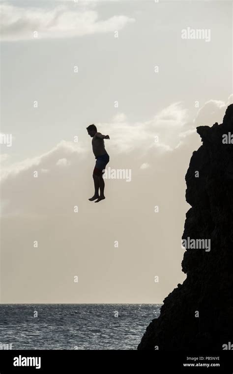 Woman Jumping Off Cliff Into The Ocean Stock Photo Download Image Now B05