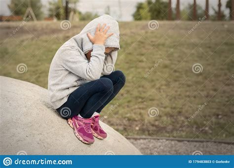 Upset Sad Depressed Little School Girl Sitting Alone At City Street Park Clutching Head. Upset 