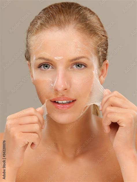 Foto De Young Woman Peeling Off A Facial Mask Smiling Do Stock Adobe