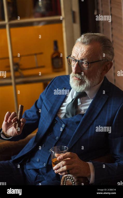 In Chair Sitting Senior Business Man With Cigar And Whisky Gray Hair