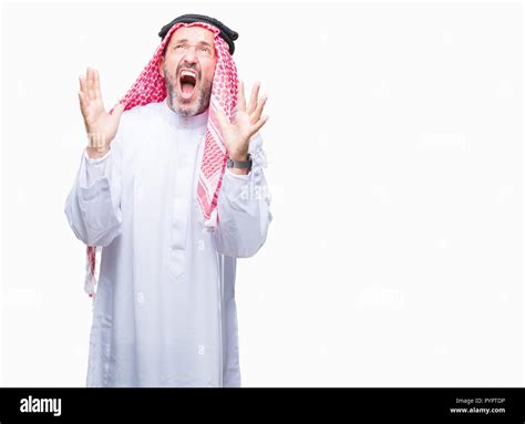 senior arab man wearing keffiyeh over isolated background crazy and mad shouting and yelling