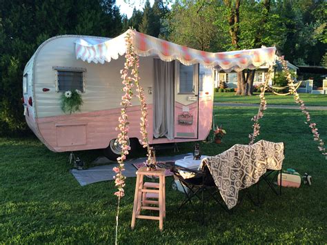 A Pink Trailer Parked On Top Of A Lush Green Field Next To A Picnic Table