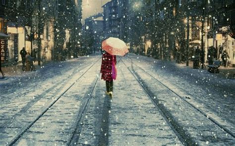 Woman Walking Alone Along A Cobblestone Road At Night In The Rain Snow