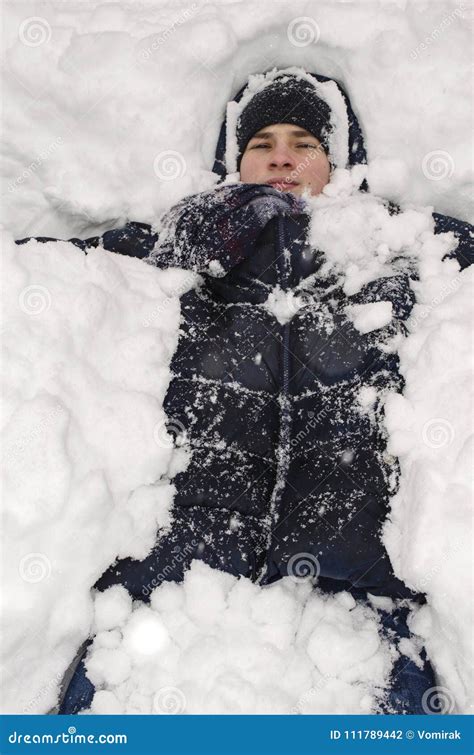 Teenager Boy Lies In Deep Snow Under A Heavy Snowfall Stock Photo