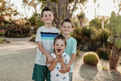 Portrait Of Three Young Siblings Smiling In Sunny Cactus Garden Stock