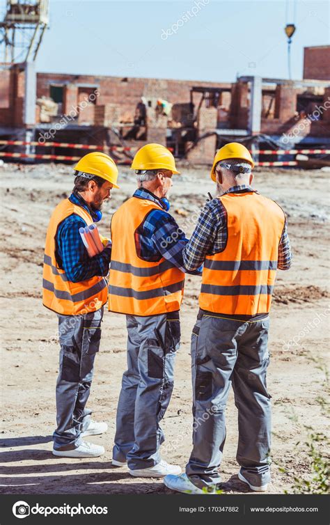 Three Workers At Construction Site Stock Photo By ©arturverkhovetskiy