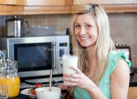 smiling woman having an healthy breakfast in a kitchen at homeの写真素材 [31406612] イメージマート