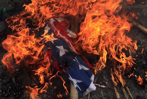 A Burning Us Flag Is Seen On The Ground After It Was Set On Fire